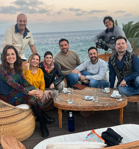 Grupo de amigos y colaboradores de Fórmula Triple Rosa sentados en una terraza frente al mar